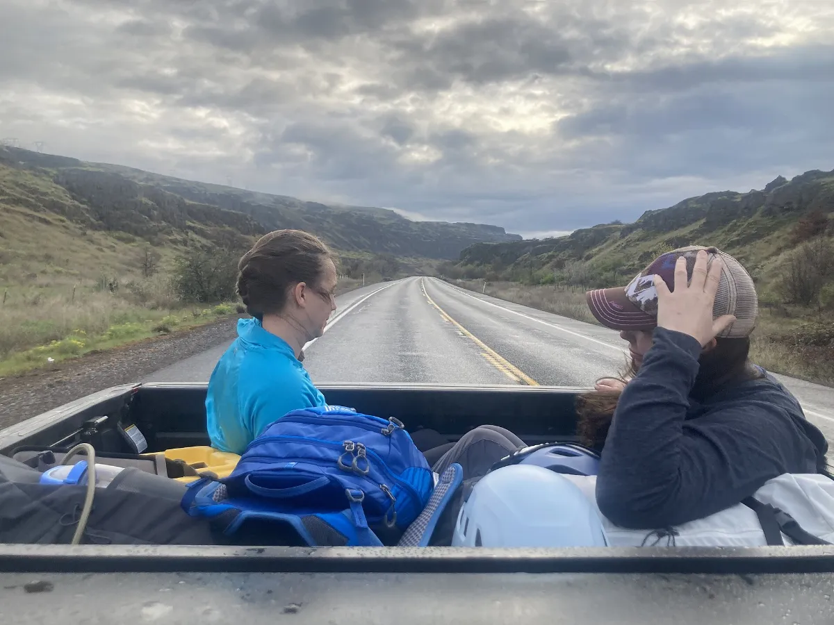 Two women in the back of a pickup truck on a rural road